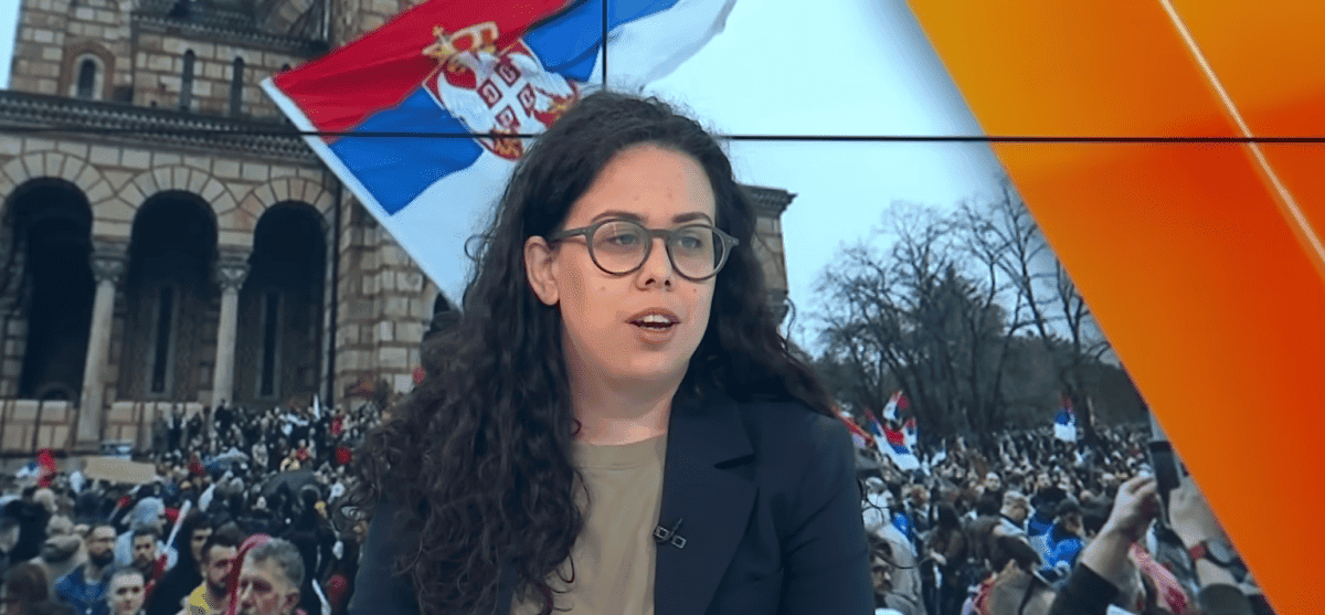 Fotografija: Sofija Popović govori ispred ekrana lkokojiprikazuje demonstracije