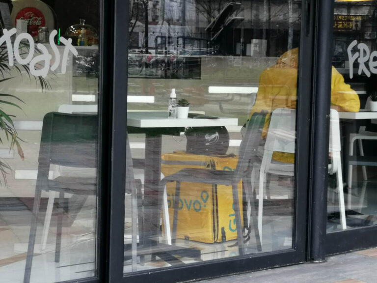 dostavljač Glova čeka da preuzme dostavu i jednom restoranu